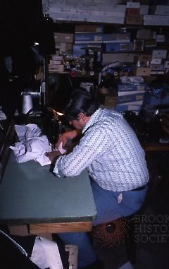 [Inside Reliable and Frank's, employee sewing a garment]