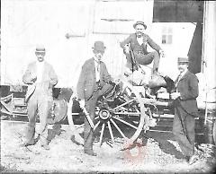 [Four men with wagon in front of box car]