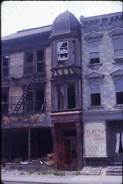 [Damaged townhouses with handwritten advertisement]