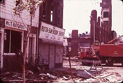 [Rubble in front of two storefronts]