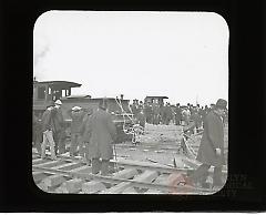 [Workers securing rope on railroad locomotive at move of Hotel Brighton]