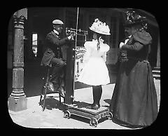 Views: U.S., Brooklyn. Brooklyn, Coney Island. View 009: Coney Island (girl getting weighed on boardwalk) 1900.