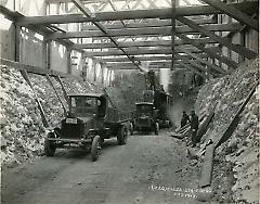 [Workers and trucks in subway tunnel]