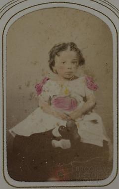 [Girl Seated Wearing Bow-Trimmed Dress]