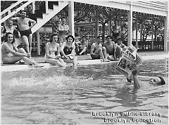 [Young man reading newspaper in pool]