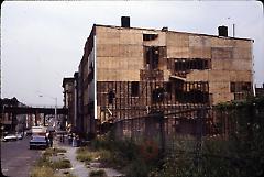 [Side view of a building partially covered in plywood]