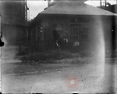 [Three men in front of a brick building