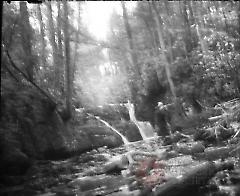[Hunter in stream by waterfall]