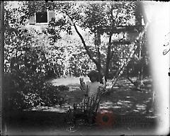 [Little girl with doll and doll carriage in yard]