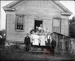 [Woman and children in front of frame building]