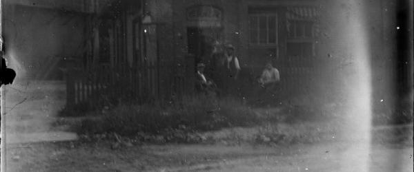 [Three men in front of a brick building