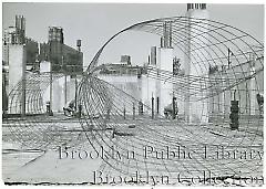 [Three construction workers seen through wire netting]
