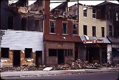 [Heavily damaged storefronts and homes]
