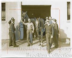 [Two stablehands with horses at armory]